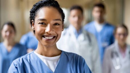 Happy chief nurse working at the hospital with a group of healthcare workers and looking at the camera smiling - medical staff concepts