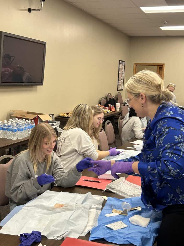 Meghan Lyerly assists high school students with a suturing activity during UAMS Northeast A Day in the Life event.