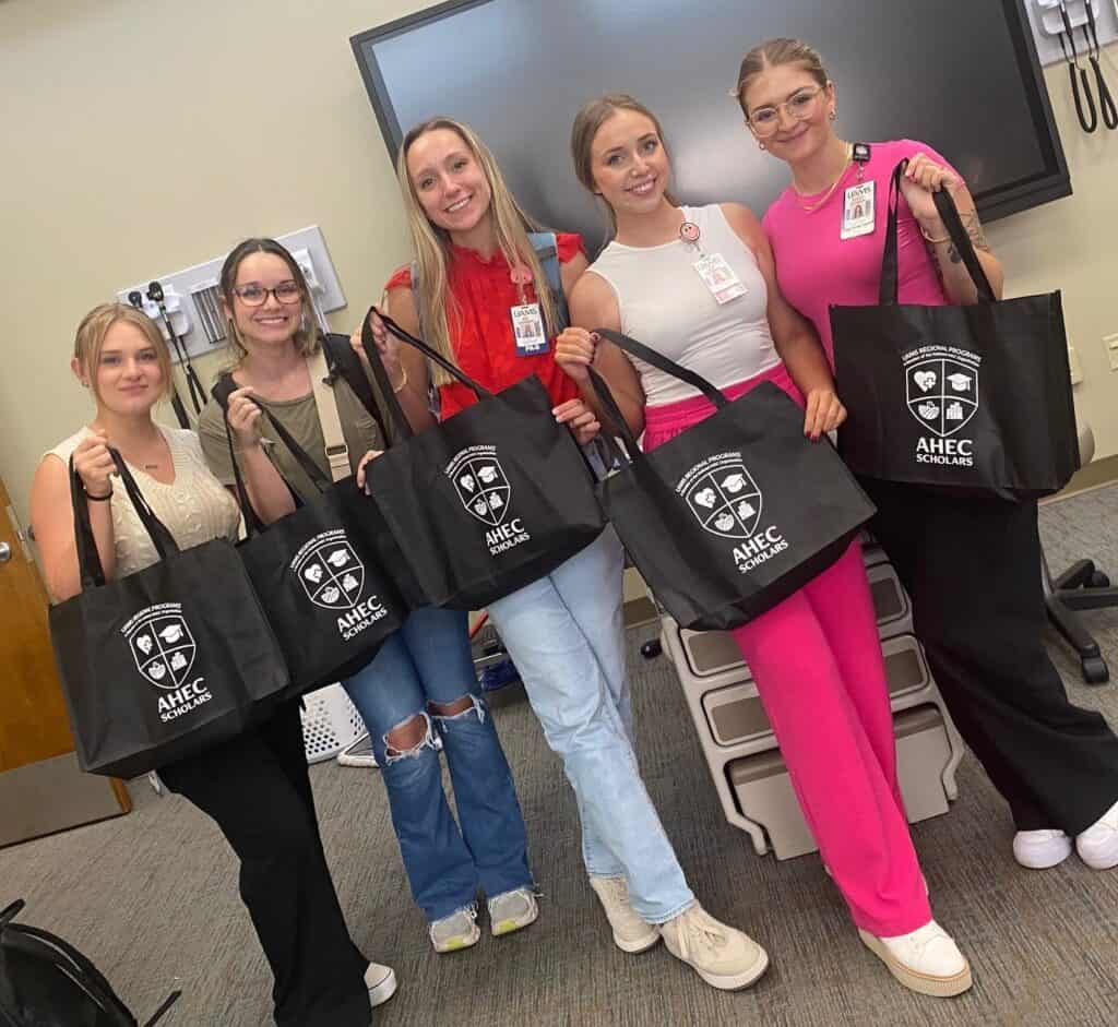 Honors in Underserved in Primary Care students showing AHEC tote bags