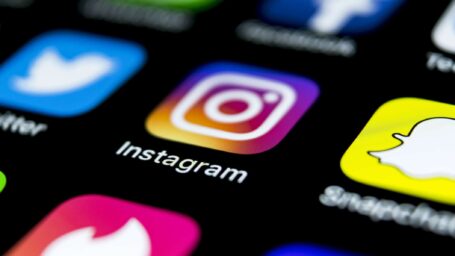 Apple iPhone X on office desk with icons of social media network instagram application on screen. Social network. Starting social media app. Photo taken at company office